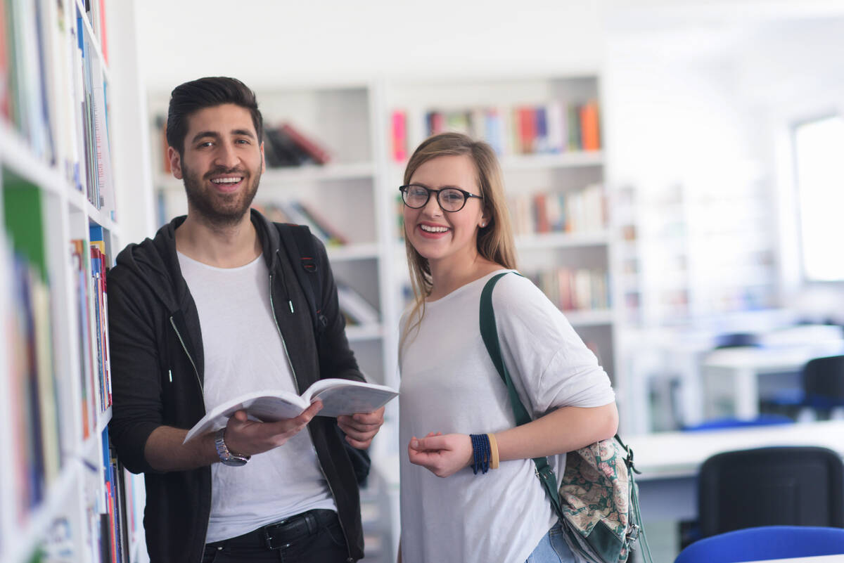Två glada studenter på ett bibliotek.